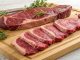 Different cuts of steak arranged on a wooden board, highlighting lean beef options with the least fat content for a healthier choice.