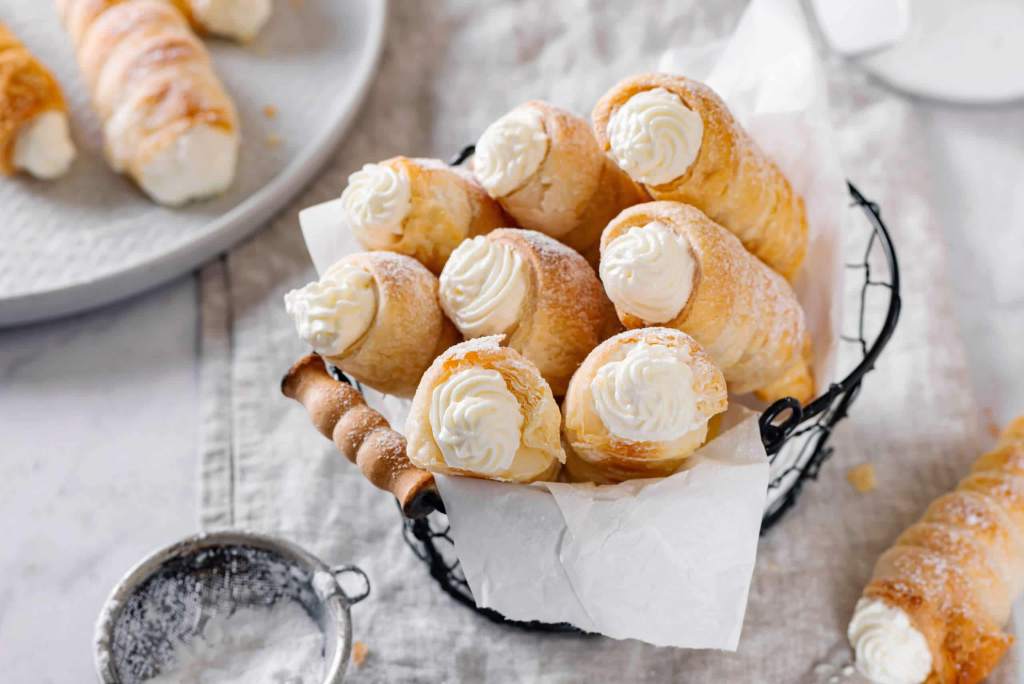 Creamy ricotta and semolina filling being spooned into shaped pastry cones