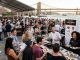 Guests sampling wine and gourmet food at the NYC Wine & Food Festival Grand Tasting Village with Manhattan skyline in the background