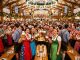 Crowds of visitors in traditional dirndls and lederhosen celebrating inside a packed Oktoberfest beer tent in Munich
